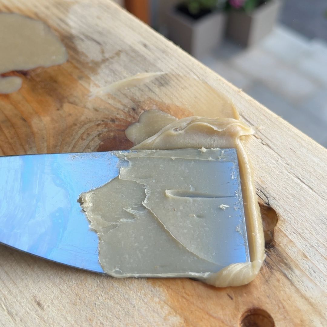 Epoxidharz mit Spachtel in Astloch eingebracht und glattgezogen – Holzreparatur ohne Hohlräume vorbereitet